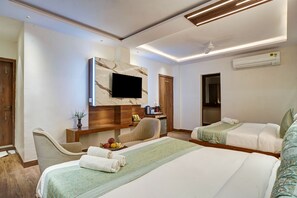 Une chambre d’hôtel avec deux lits, un bureau doté d’un téléviseur à écran plat, un petit réfrigérateur et un appareil de climatisation.