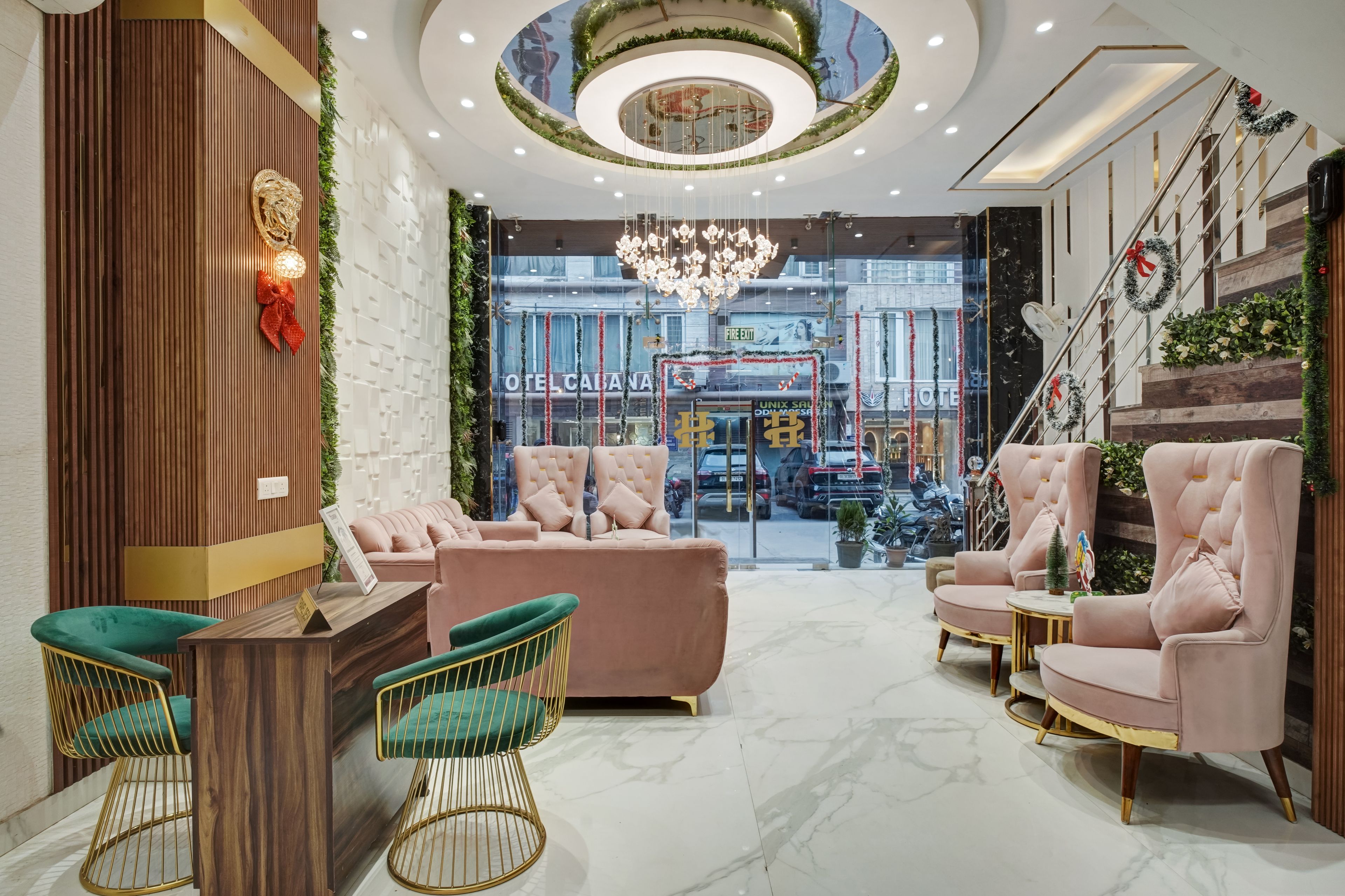 A hotel lobby with a central seating area, a staircase, and a view of the street.