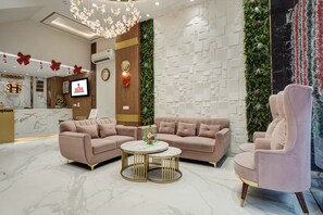 A hotel lobby with a reception desk, two sofas, a round coffee table, and a decorative wall with greenery. - Hotel Saina International - Newly Built  (New Delhi)