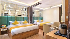 Een hotelkamer met twee bedden, een bureau, een stoel, een koffiezetapparaat en een plafondventilator.