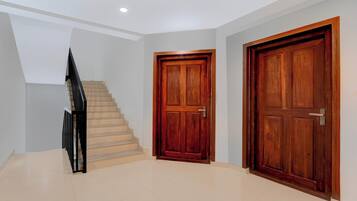 Un interior moderno con una escalera, dos puertas de madera y un suelo de baldosas.