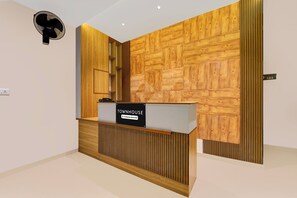 A reception desk with a sign indicating it is company-serviced, a wall with a geometric wood pattern, and a number sign '103' on the wall.