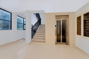 A spacious interior with a staircase, an elevator, and large windows.
