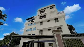 Un edificio de varios pisos con techo plano, grandes ventanales y un balcón en el último nivel.