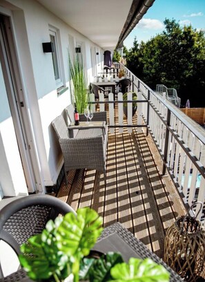 A balcony with wicker furniture, a table, and a potted plant. - Holiday Apartment 713 (Winterberg)