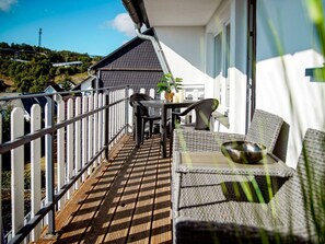 A balcony with a wooden floor, white railing, and a table with chairs. - Holiday Apartment 713 (Winterberg)