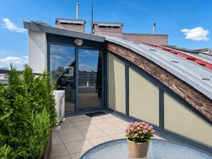 A modern building with a sloped roof, a glass door entrance, and a potted plant on the balcony. - MARGI City 13 Apartment (Szczecin)
