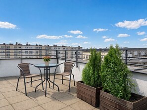 A rooftop terrace with two wicker chairs, a small round table, and a potted plant. - MARGI City 13 Apartment (Szczecin)