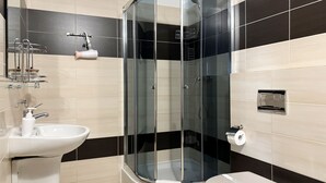 A modern bathroom with a glass-enclosed shower, a white sink, and a toilet. - MARGI City 13 Apartment (Szczecin)