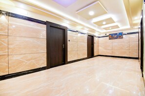 A hallway with marble flooring, wooden doors, and recessed ceiling lighting. - Townhouse Puri Former Hotel Narashingha (Puri)