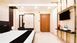 A hotel room with a bed, a mirror, a wardrobe, a television, and a small table with toiletries. - Townhouse Puri Former Hotel Narashingha (Puri)