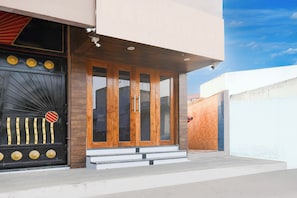 A modern building entrance with a black gate, a wooden door, and a small set of steps leading up to the door. - Townhouse Puri Former Hotel Narashingha (Puri)
