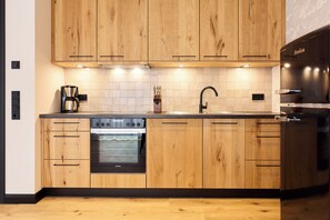 Eine moderne Küche mit Holzschränken, einem Einbauofen, einer Kaffeemaschine und einem Spülbecken.