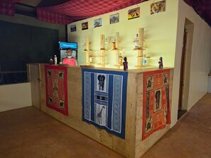Un mostrador de recepción con una pantalla de televisión, estantes de madera con diversos objetos y paneles decorativos.