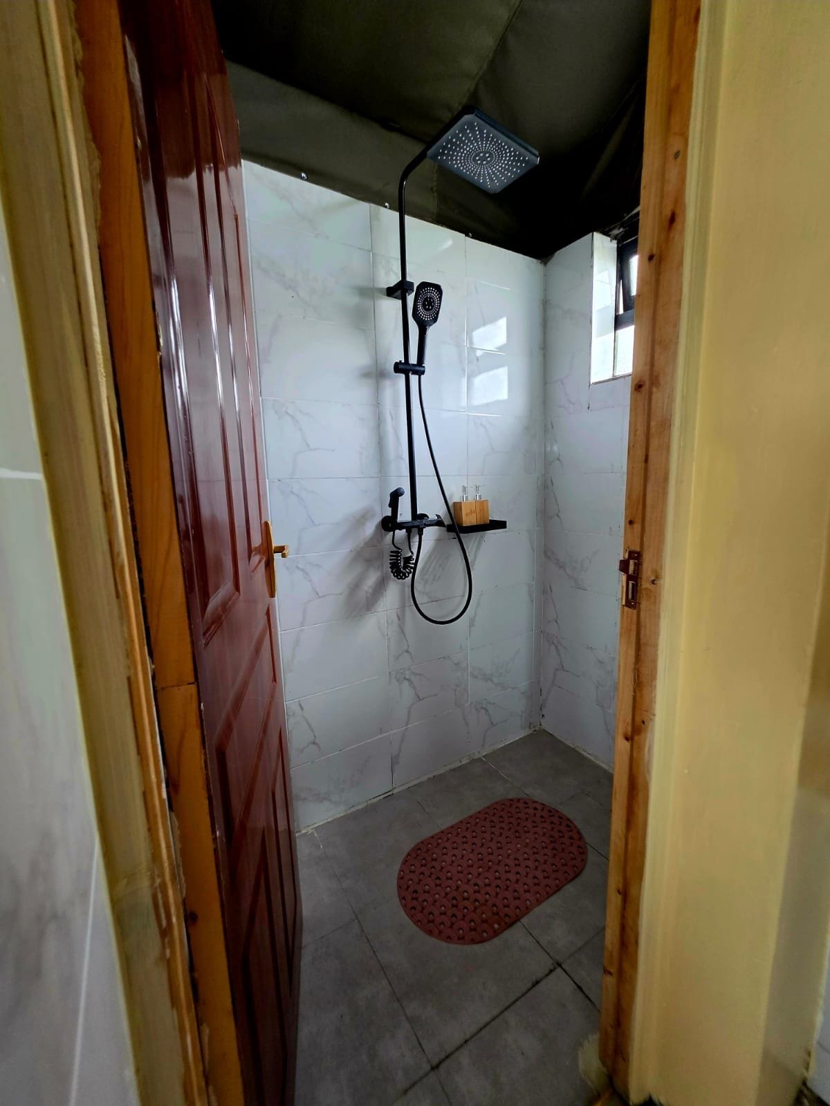 Un espacio de ducha con un cabezal de ducha manual, un cabezal de ducha empotrado y un cabezal de ducha manual sobre un soporte.