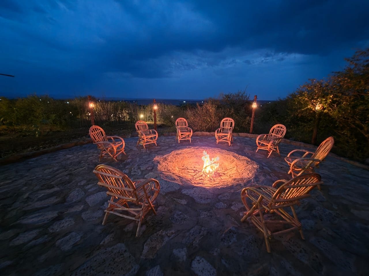 A fire pit with chairs arranged around it on a stone patio.