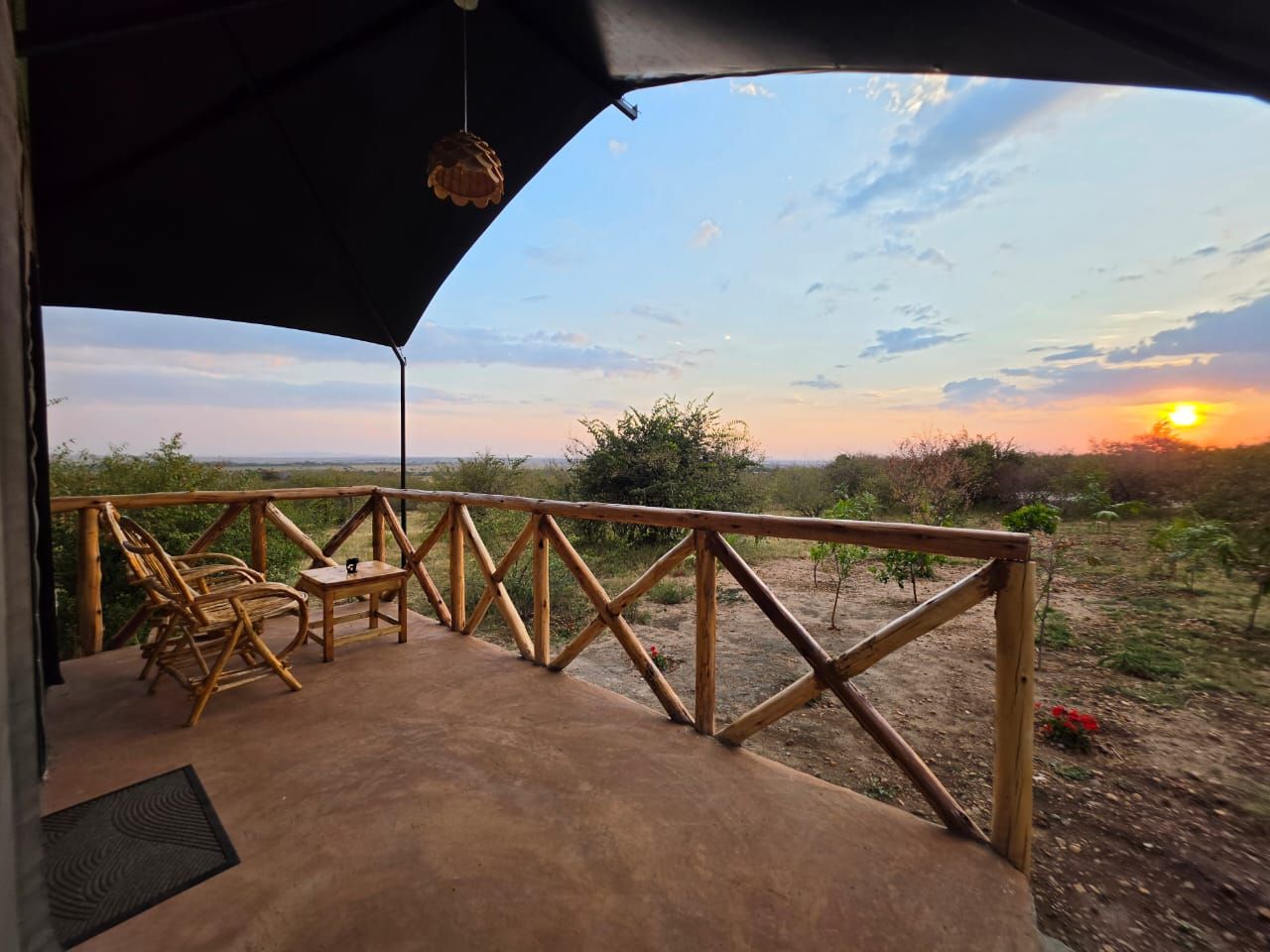Una terraza exterior con baranda de madera, una mesa y sillas.