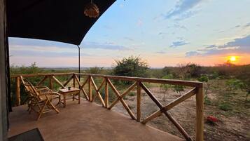 Una terraza exterior con baranda de madera, una mesa y sillas.