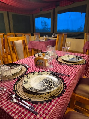 Comedor con mesas dispuestas para dos, con manteles estampados y platos decorativos.