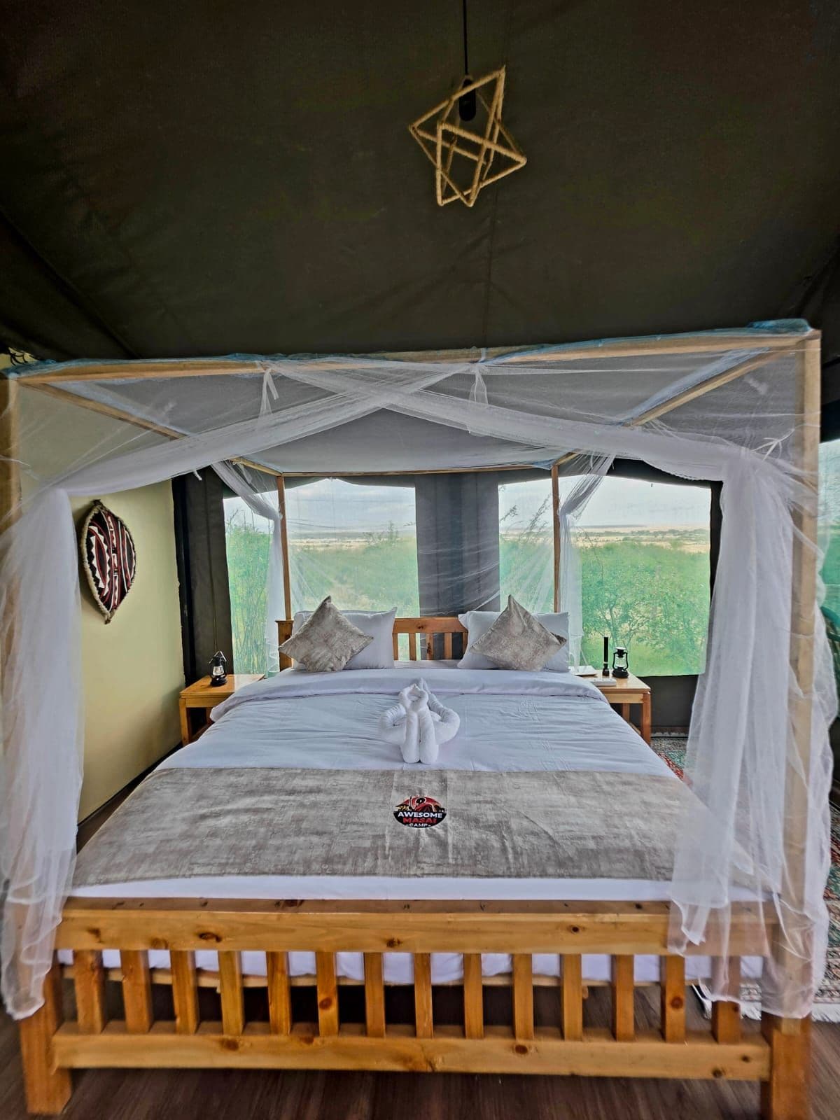 Una habitación con tienda de campaña, una cama, un adorno colgante y vistas al exterior.