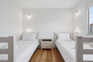 Habitación doble con dos camas, una mesita de noche y una ventana.