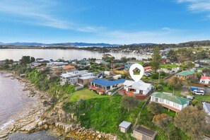 Una zona residencial costera con casas, un lago y montañas al fondo.