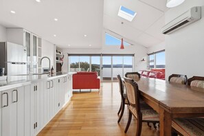 A modern kitchen with white cabinets, a wooden dining table, and a red sofa.