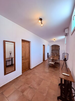 Ein geräumiger Flur mit einer Holztür, eine Essecke mit Tisch und Stühlen und ein Spiegel an der linken Wand.