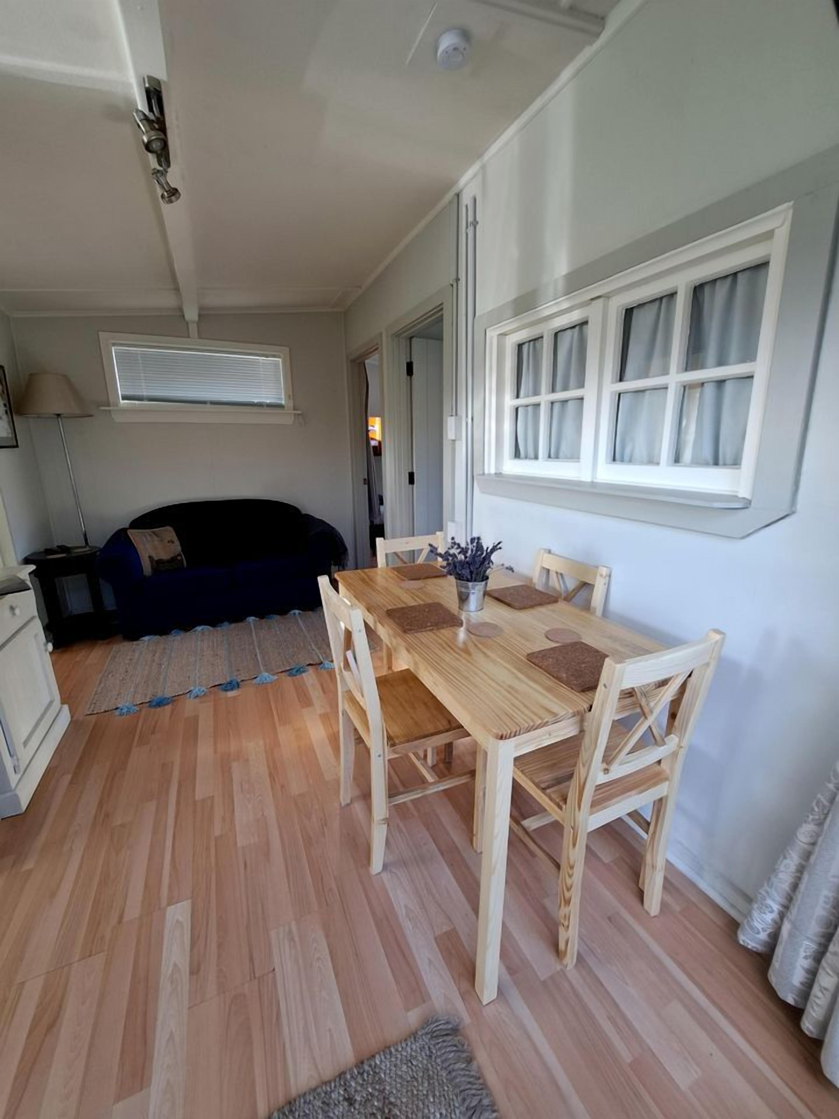 A compact living space with a dining area, a sofa, and a window.