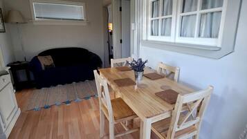 A compact living space with a dining area, a sofa, and a window.