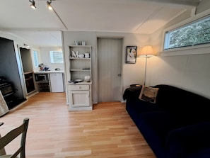 A compact living space with a kitchenette, a dark blue sofa, and a lamp.