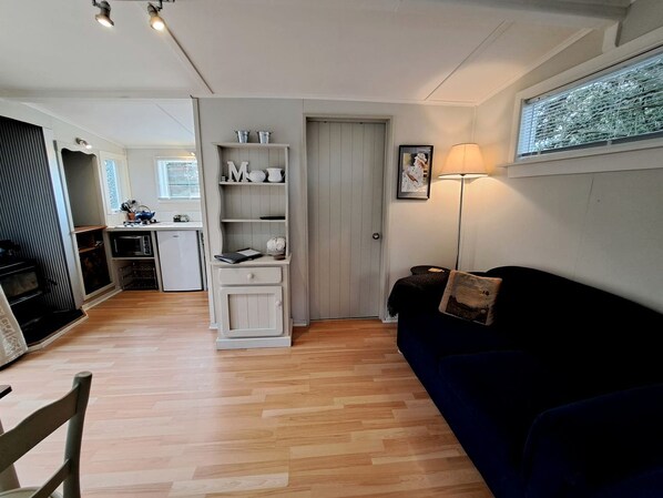 A compact living space with a kitchenette, a dark blue sofa, and a lamp.