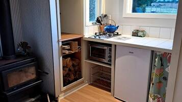 A compact kitchen with a built-in oven, a small refrigerator, and a window providing natural light.