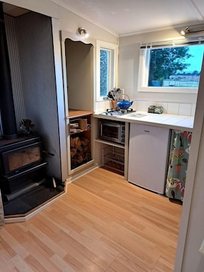 A compact kitchen with a built-in oven, a small refrigerator, and a window providing natural light.