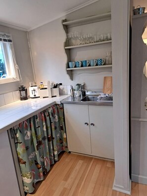 A compact kitchen with a white countertop, a built-in sink, and a window above the sink.