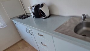 Ett kök med en diskho i rostfritt stål, en gasspis och en kaffebryggare på bänkskivan.