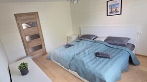 Ett modernt sovrum med en säng, sängbord, en liten krukväxt och en inramad tavla på väggen.