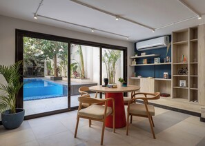 A modern living room with a pool view, a round table with chairs, and a bookshelf. - Amazing Deal at 22 by Spacey #57 (cairo)