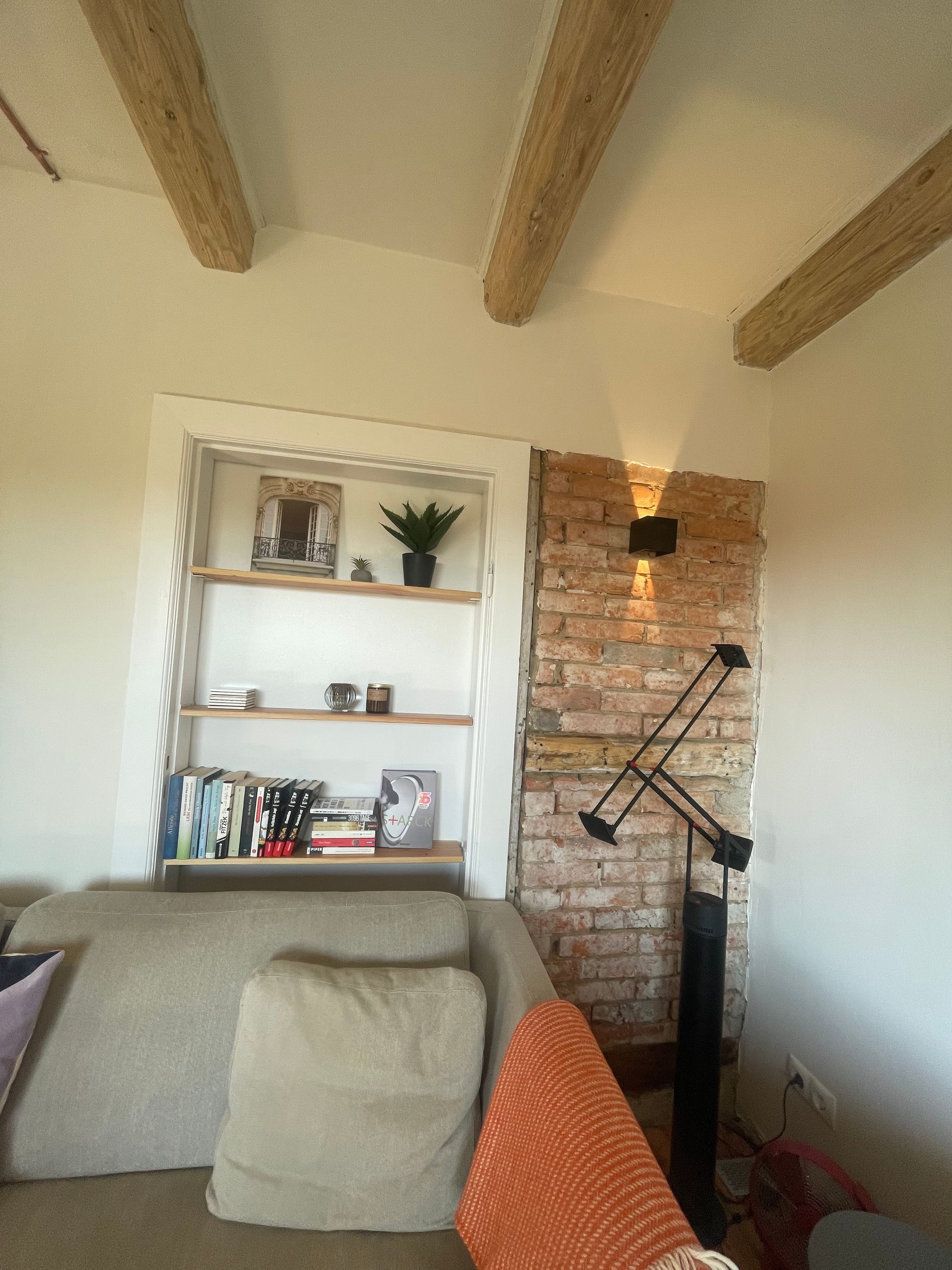 A living room with a brick accent wall, a bookshelf, and a modern floor lamp.
