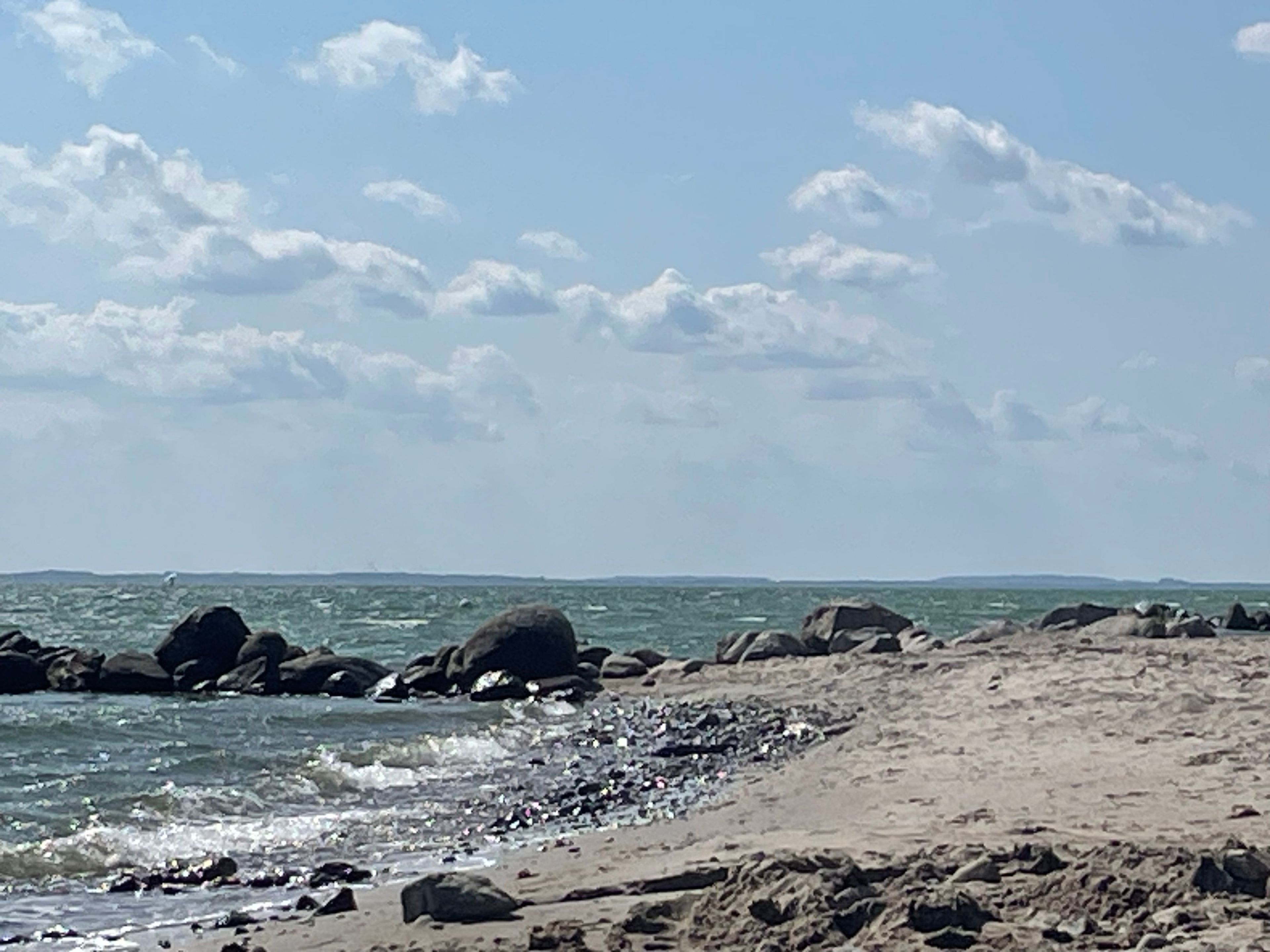 Una playa con terreno rocoso y olas.
