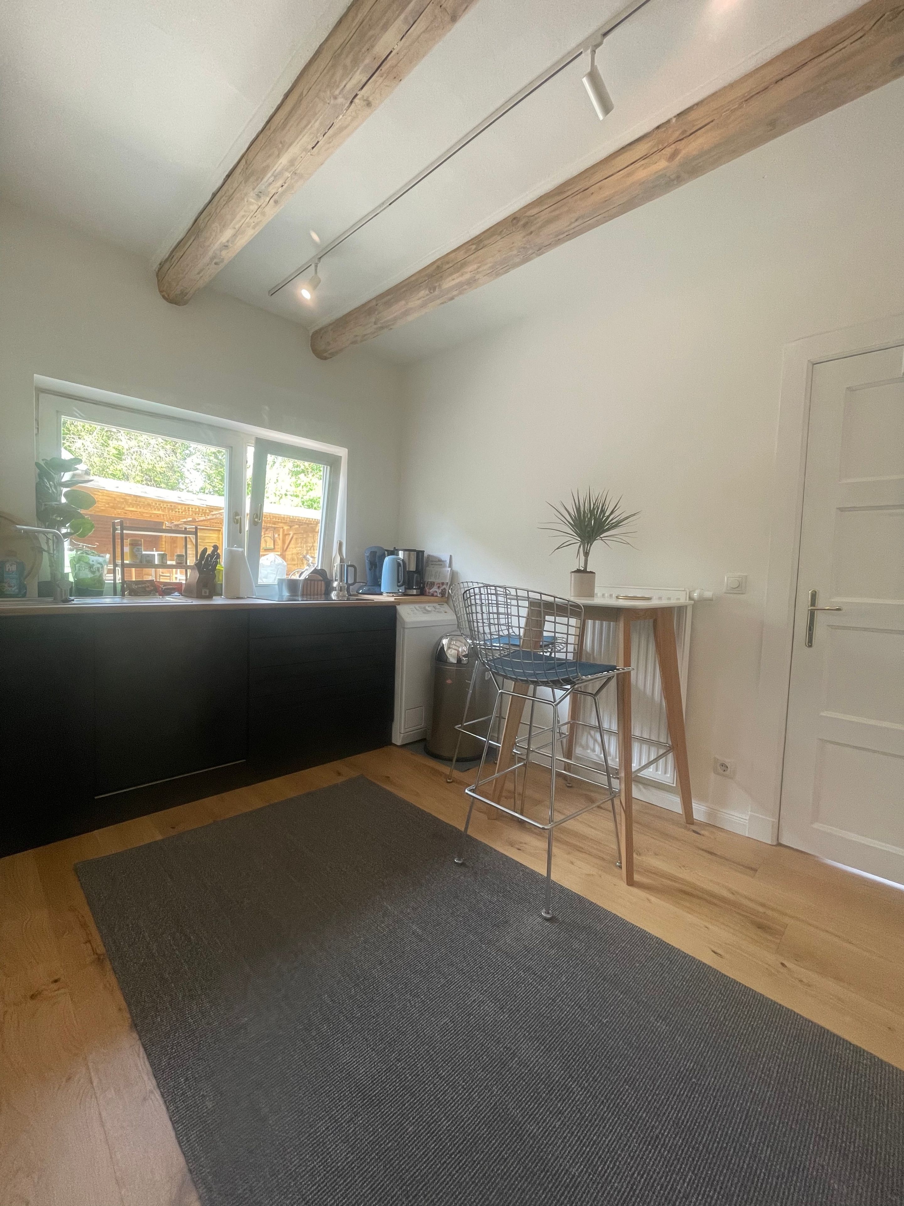 A modern kitchen with a built-in stove, a dining area with a table and chairs, and a large window providing natural light.