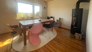 Ein Zimmer mit einem Holztisch, Stühlen, einem Kamin und einem großen Fenster.