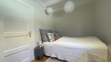 A bedroom with a bed, a bedside table, a lamp, and a door.