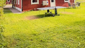 Una casa roja con un porche techado, una mesa y sillas.