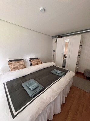 A neatly made bed with a white and black bedspread, two pillows, and folded towels. - Vrbo Property (Tärnsjö)