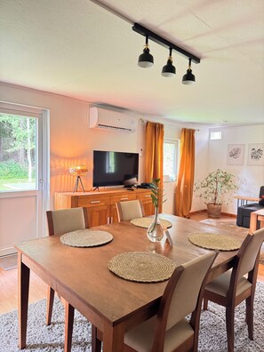A dining area with a wooden table, chairs, and a TV in the background. - Vrbo Property (Tärnsjö)