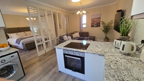 A compact kitchen with a built-in oven, a washing machine, and a dining area with a sofa and a coffee table.
