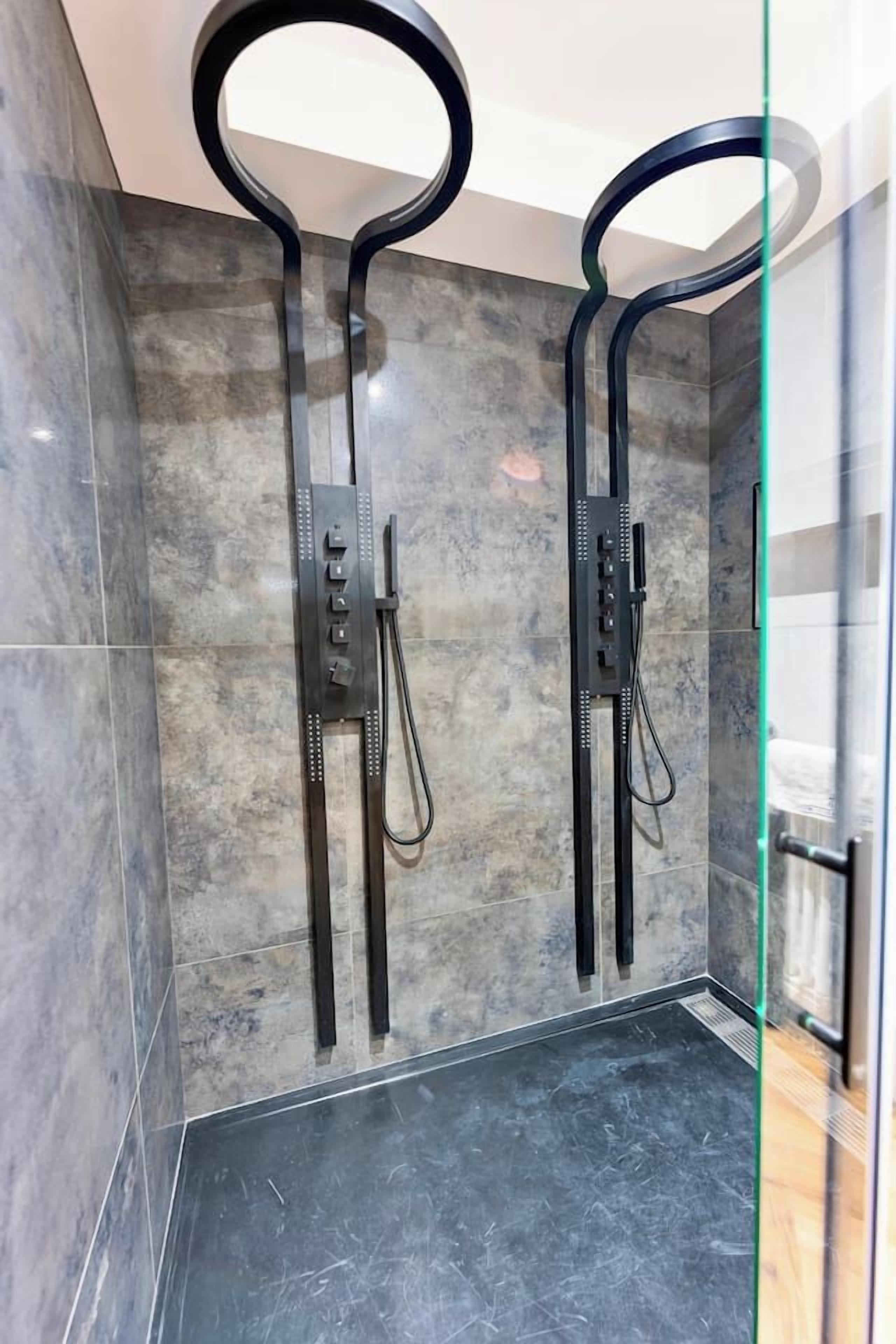 A modern shower enclosure with a glass door and a control panel.