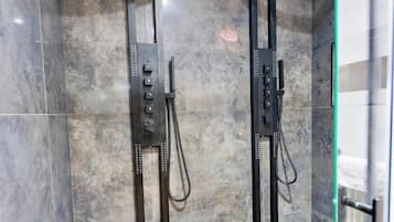 A modern shower enclosure with a glass door and a control panel.
