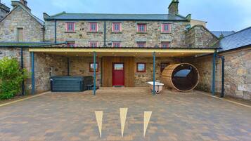A stone building with a covered entrance, a red door, and a large barrel.